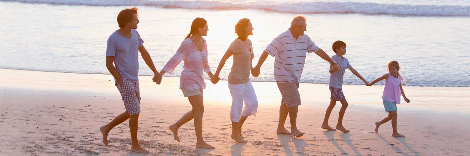 Multi genreation family of expats walking along a beach