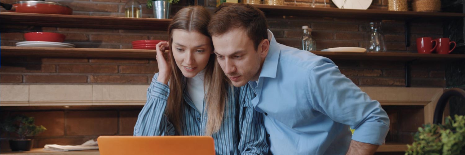 Investment strategies researched by a couple in kitchen sorting finances on laptop